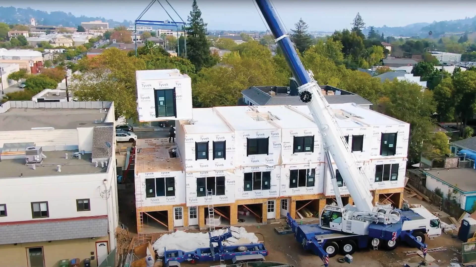 Crane setting factory-built modules on a multi-story project